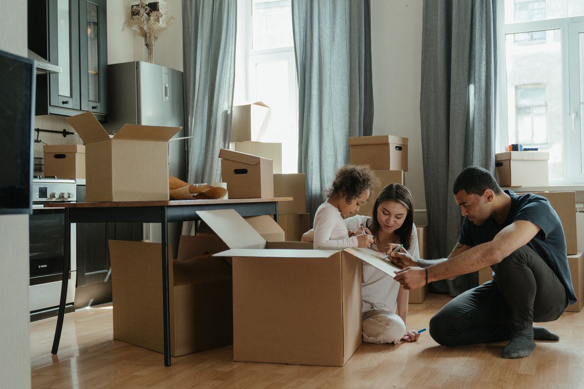 Family sitting on the floor unpacking boxes in their new home